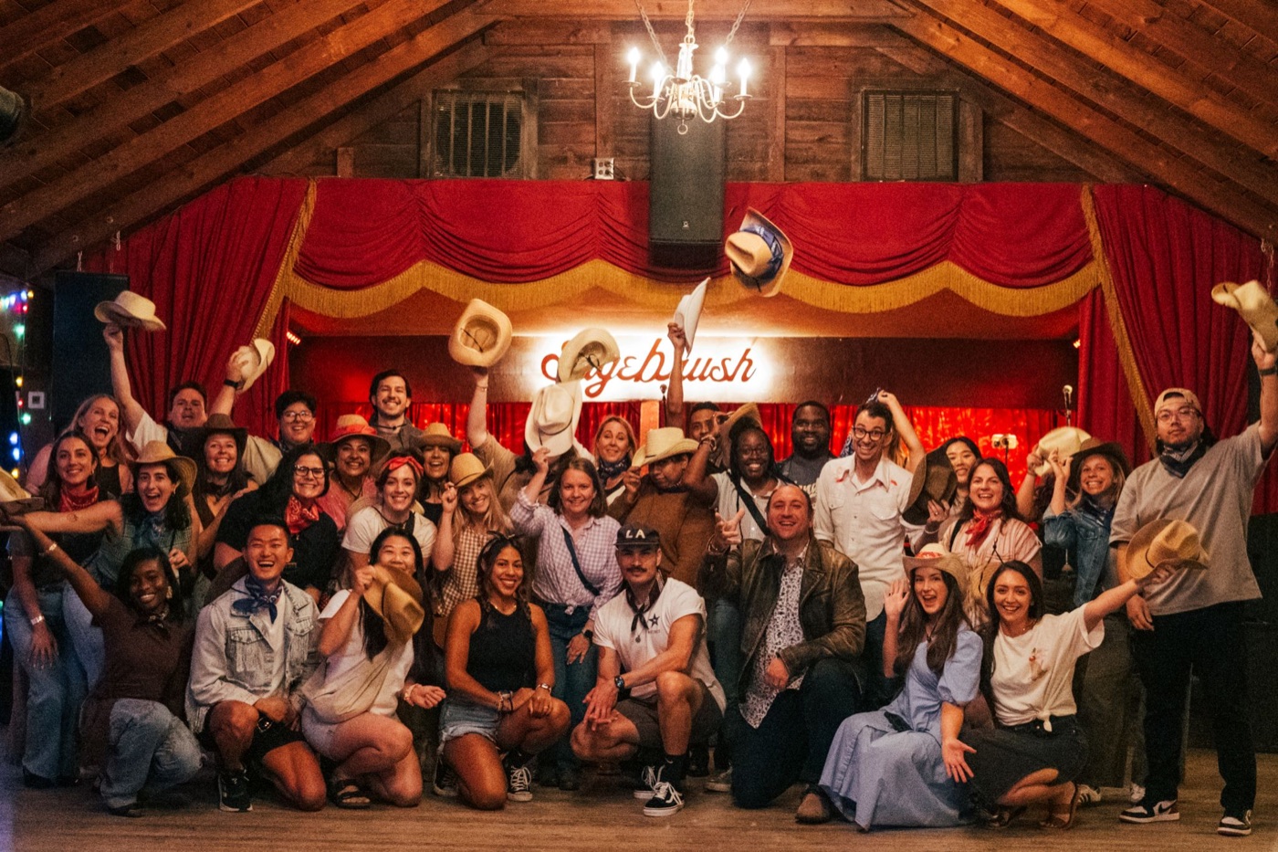 A group of honky-tonk dancers raising cowboy hats at Sagebrush dance hall in South Austin, Texas